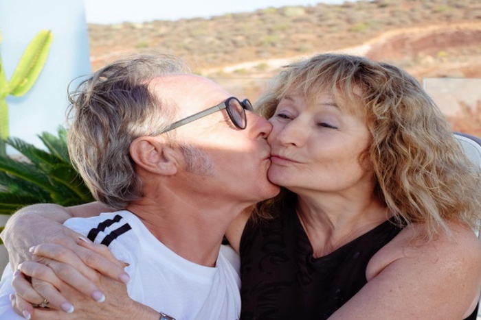 Handsome mature couple embracing exchanging cuddles and kisses enjoying moment of affection