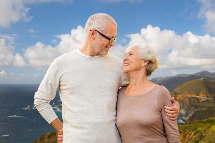 Happy senior couple hugging over coast