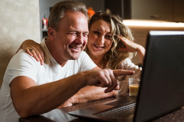 Lovely senior couple laughing at laptop