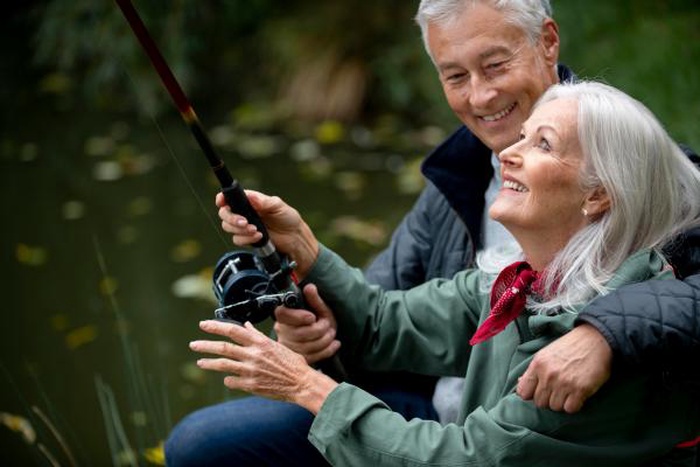 Senior couple fishing and sharing happy moments by the water