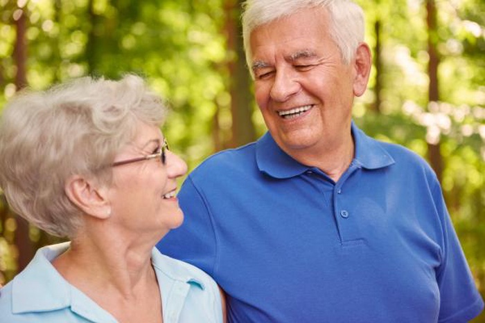 Smiling senior man and woman sharing joyful moment in forest