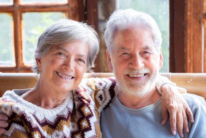 An elderly couple embracing and laughing at home