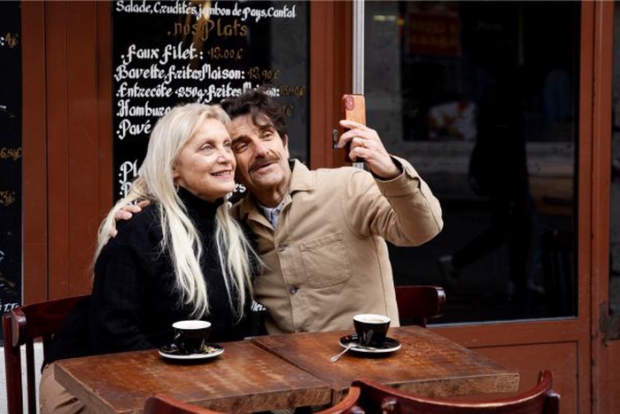Couple senior souriant en train de prendre un selfie dans un espace vert de Ganshoren, profitant d’un moment complice lors de leur sortie ensemble.