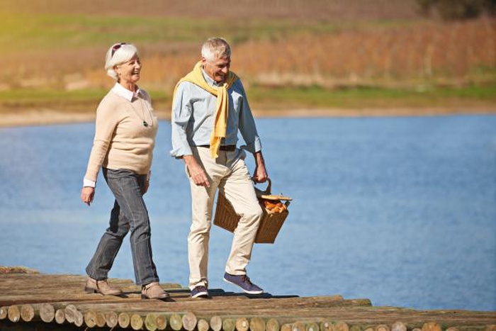happy senior couple walking  along the pier of a lake