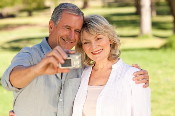 Senior couple taking selfie together in park