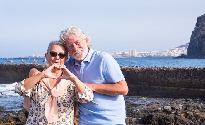 Retrato de una pareja de ancianos sonrientes de pie junto al mar