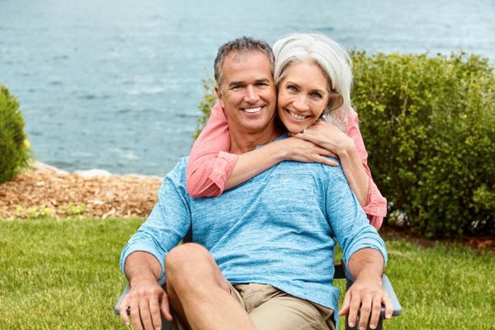 Smiling middle-aged couple embracing outdoors near the lake