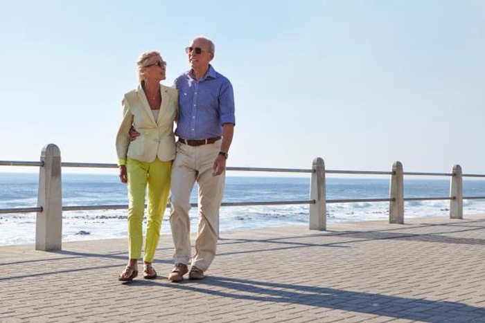 An elderly couple strolls along the seaside promenade