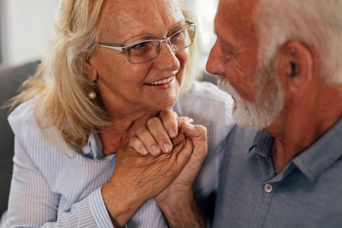 Happy senior couple in love holding hands and talking to each other focus is on woman
