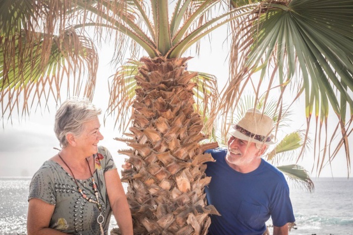 Man and woman by palm tree against sea