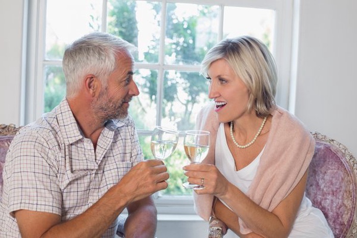 Happy mature couple with wine glasses at home