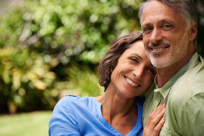 A senior couple embracing and laughing in the park