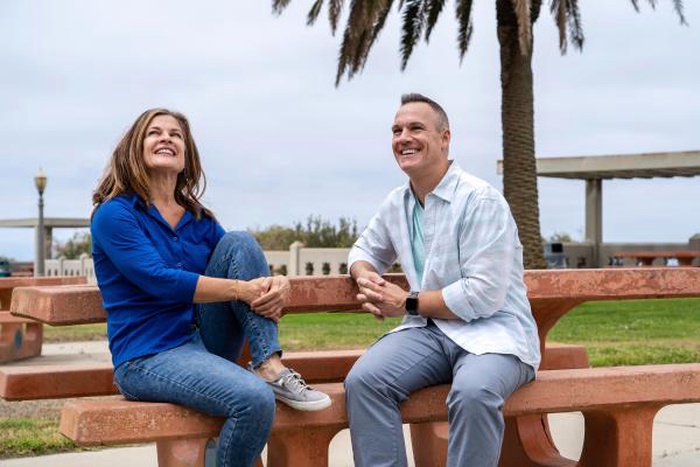 Happy mature couple laughing together on an outdoor park bench