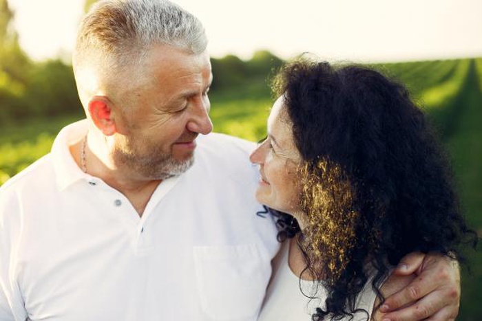 Loving mature couple gazing into each other’s eyes in a sunlit green field
