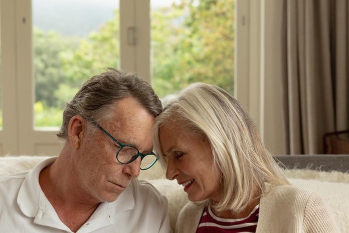 Active senior couple head to head on sofa