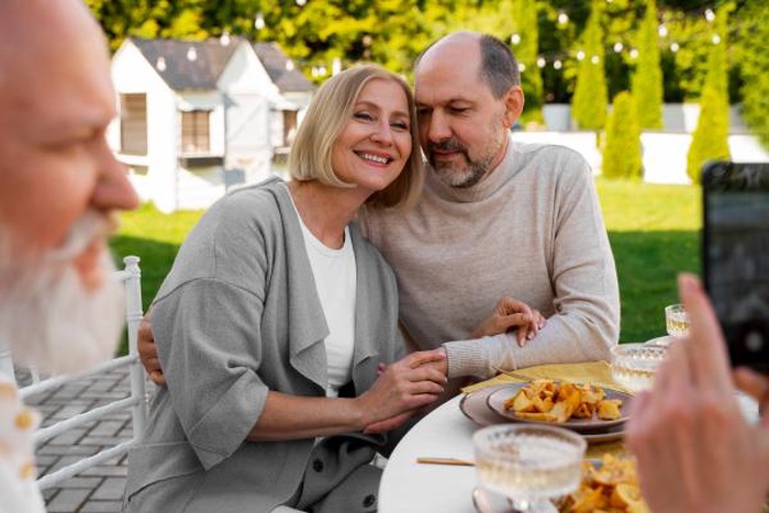 Happy senior couple posing for a photo together during an outdoor garden dinner date