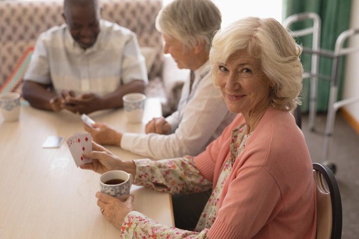 Senior woman playing cards in living room
