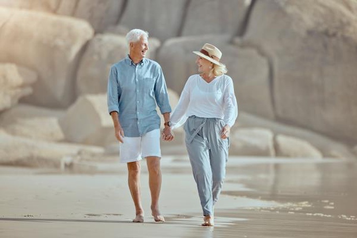A mature couple strolling along the beach during their romantic retirement vacation