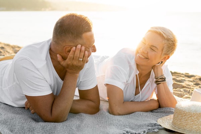 Medium shot senior couple laying on towel