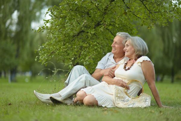 nice senior couple sitting on grass in park