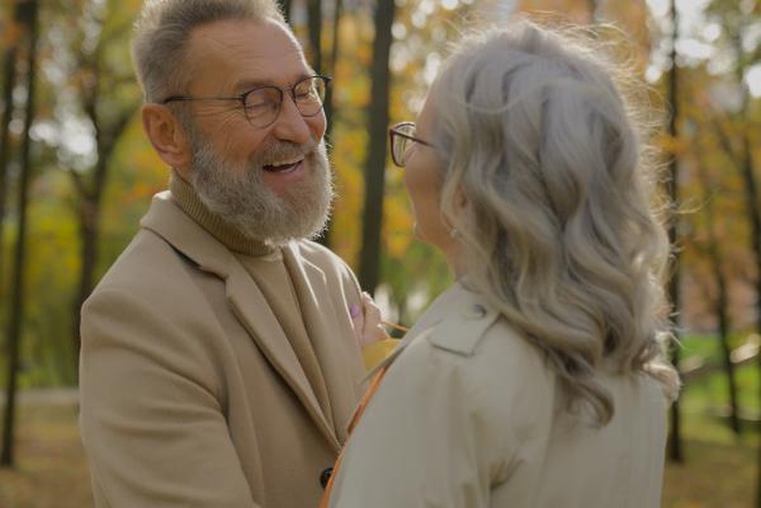 Cheerful senior couple laughing face to face in an autumn park