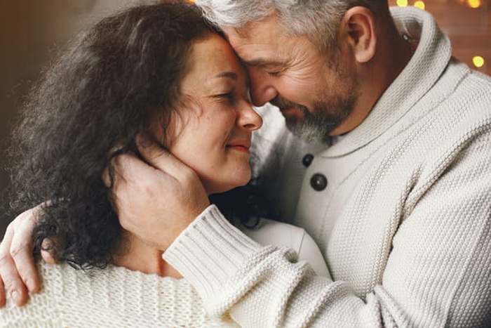 Senior couple with gift box over lights background