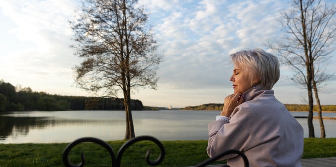 Sad and contemplative senior single near lake
