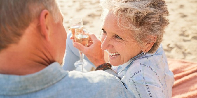 Champagne senior beach couple laughing