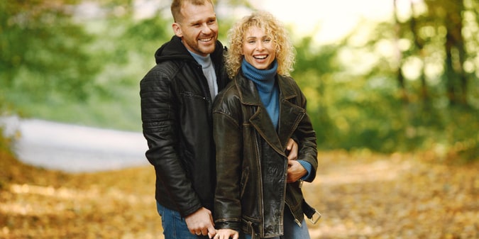 Blonde curly woman and man standing in autumn forest