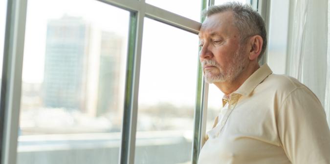senior man alone thoughtful window home