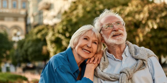 beautiful senior woman leaning at shoulder of her husband and smiling