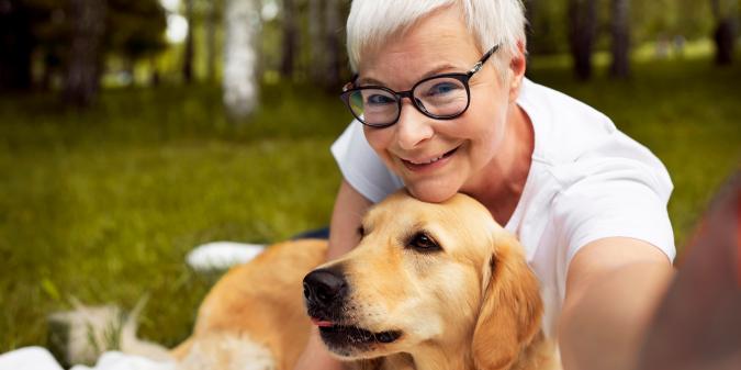Senior woman smiling with her dog outdoors