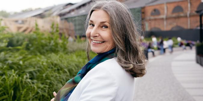 Happy senior woman smiling outdoors at 58