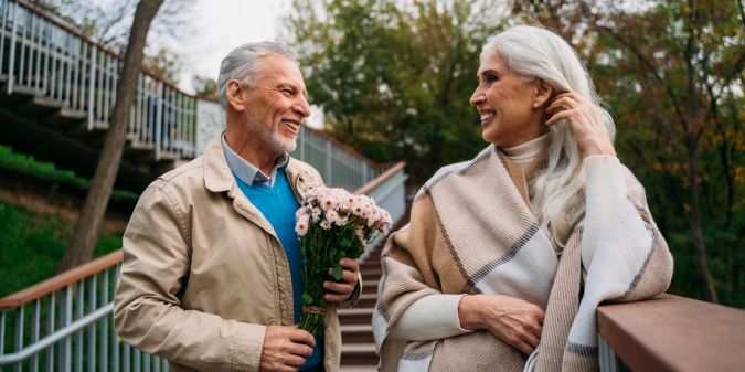 Mature man presenting flowers to a woman