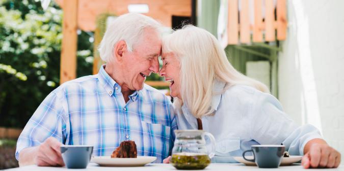 Senior couple laughing together over coffee outside