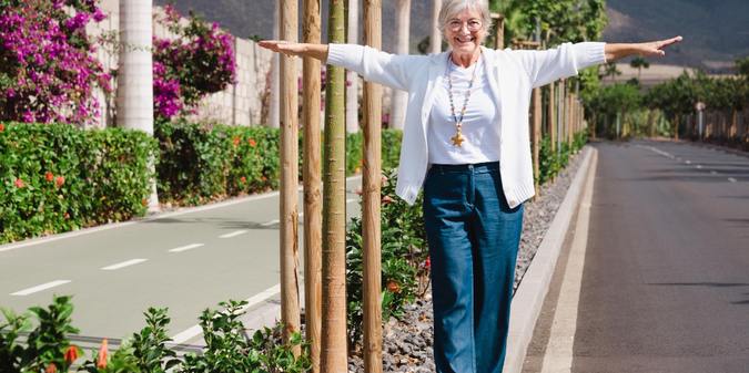 Playful mature woman walking on the roadside in balance