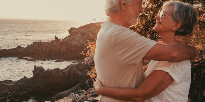 happy-senior-family-couple-embracing-face-the-sea-at-sunset