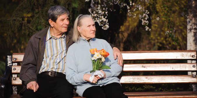 Beautiful happy old people sitting in the autumn park