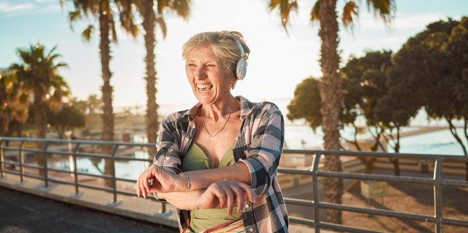 Happy old woman headphones and music on holiday