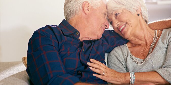 Happy care and senior couple on sofa