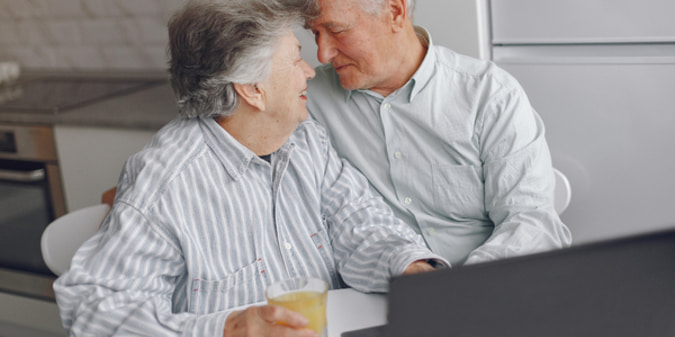 Elegant old couple sitting at home and using a laptop
