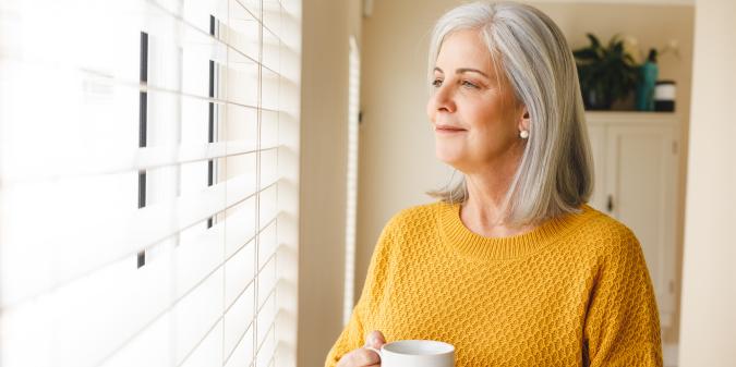 Thoughtful senior woman smiling looking out window